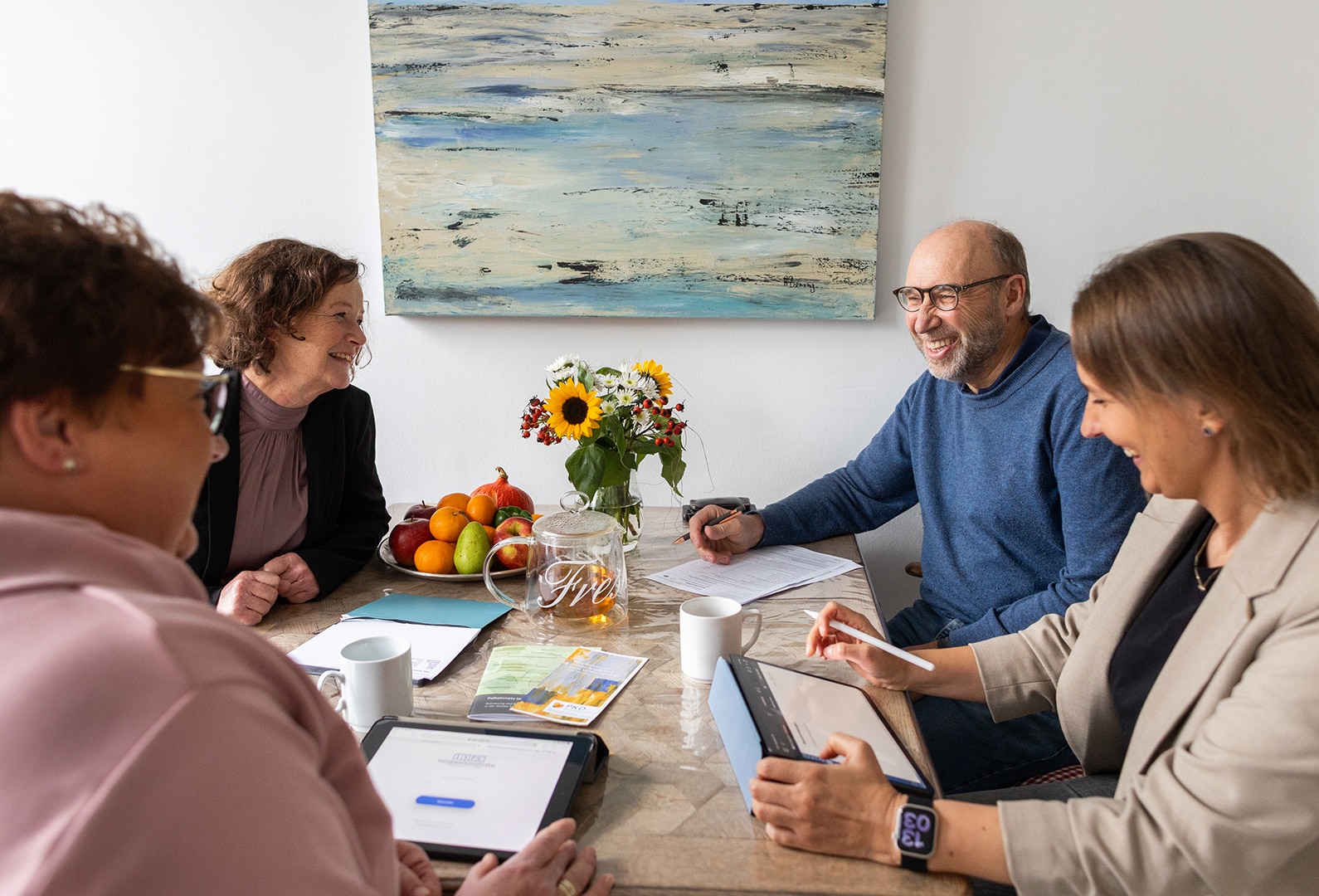 Ein Team des Palliativdienstes führt ein einfühlsames Gespräch am Tisch in gemütlicher häuslicher Umgebung.