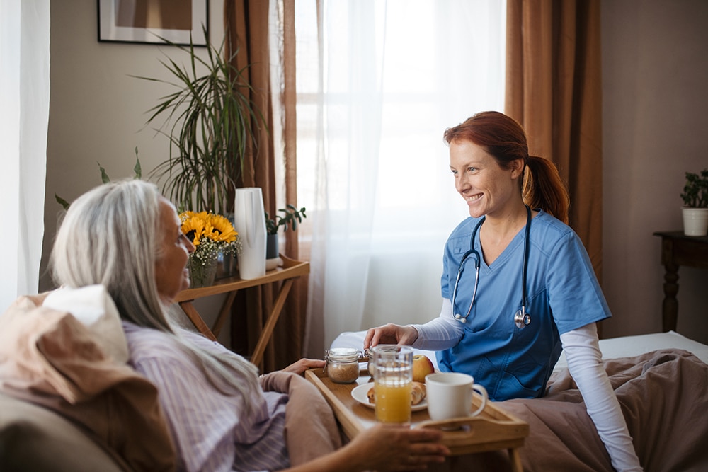 Lächelnde Pflegekraft kümmert sich einfühlsam um eine Patientin am Bett