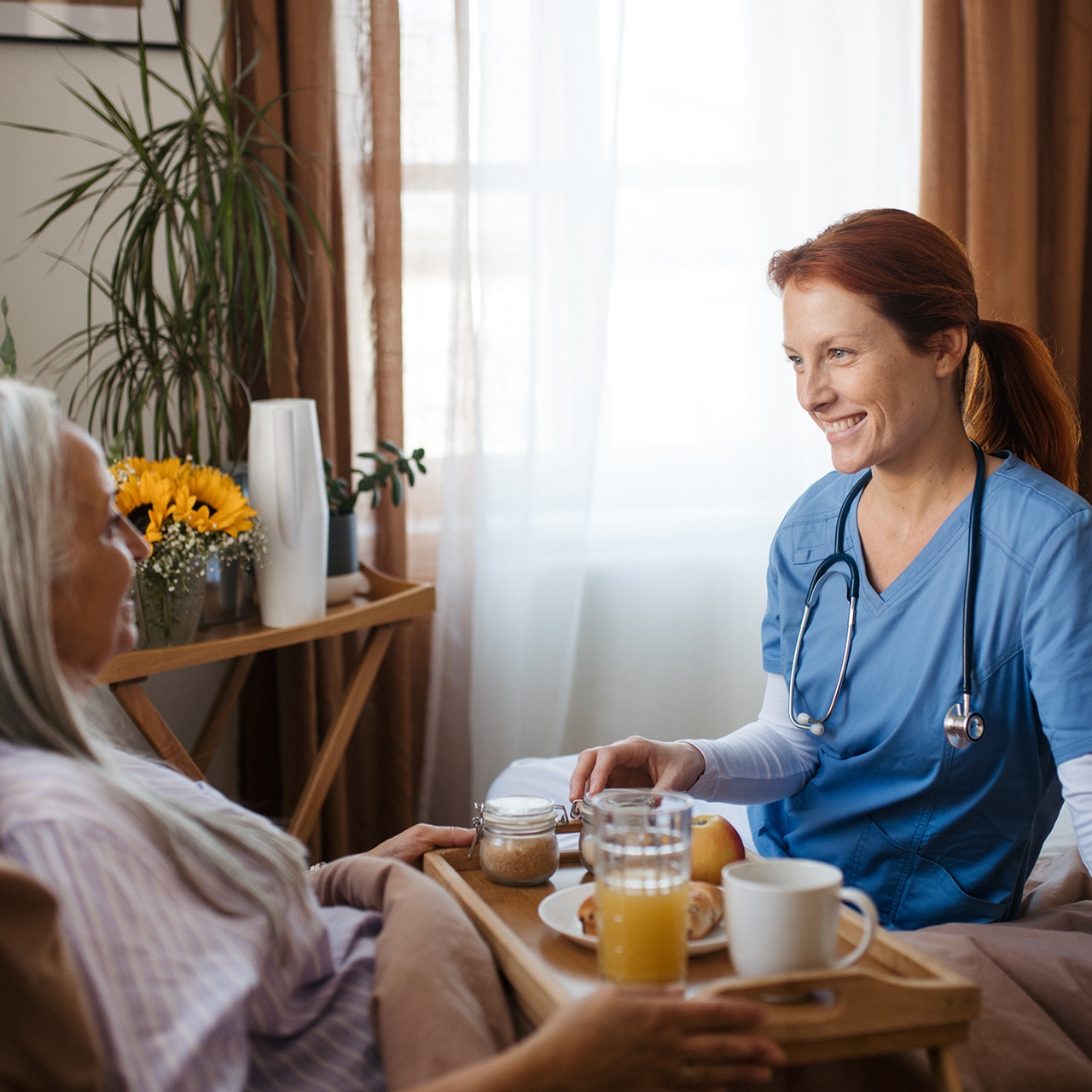Lächelnde Pflegekraft kümmert sich einfühlsam um eine Patientin am Bett