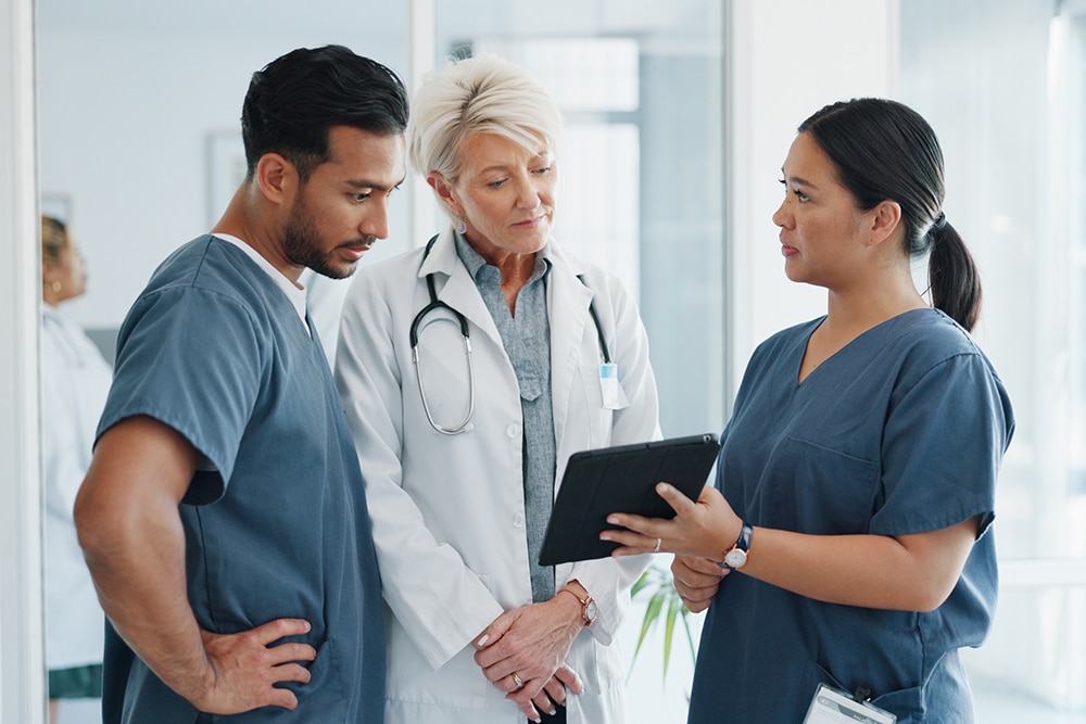 Drei medizinische Fachkräfte besprechen im Team die Behandlung eines Patienten