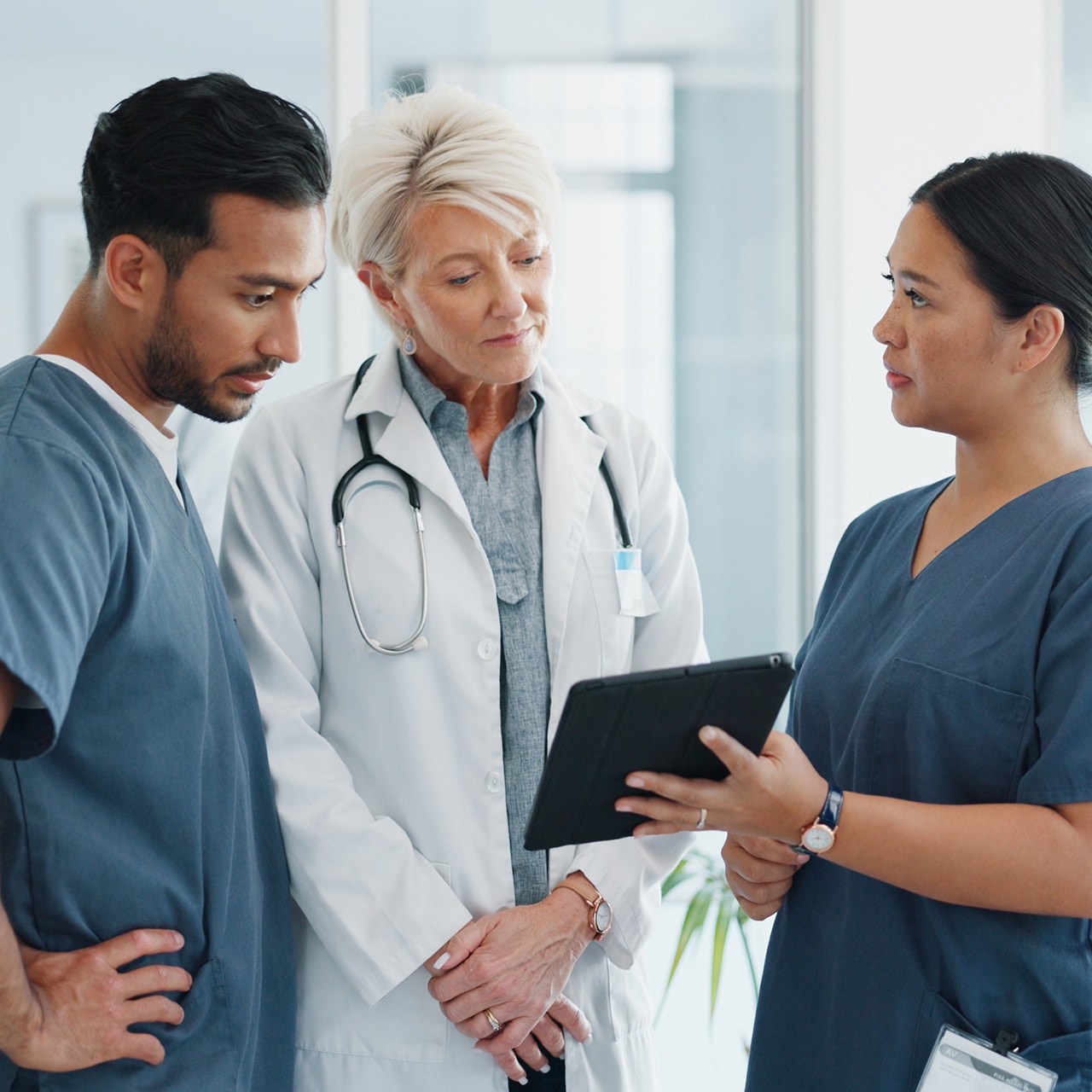 Drei medizinische Fachkräfte besprechen im Team die Behandlung eines Patienten