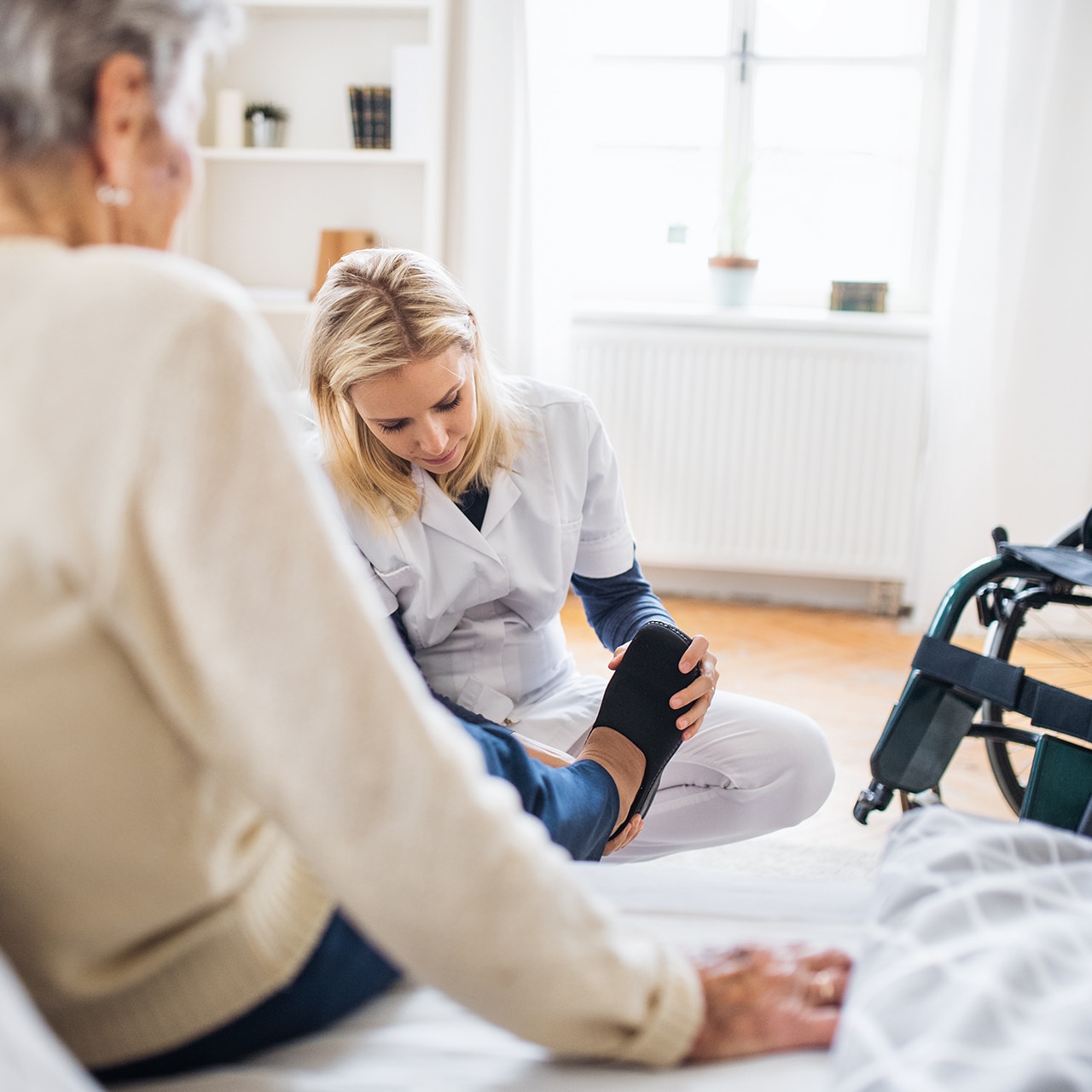 Pflegekraft hilft einer älteren Patientin einfühlsam beim Anziehen zu Hause